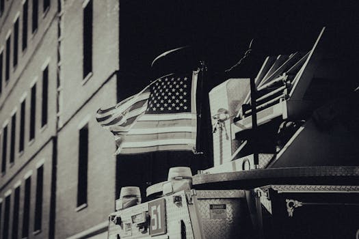 Sepia-toned image of an American flag on a fire truck in a city.
