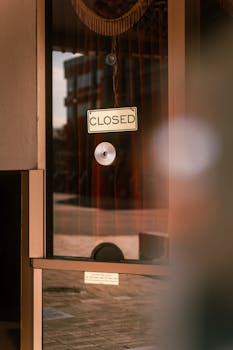 A reflective glass door displays a 'Closed' sign with subtle urban reflections.