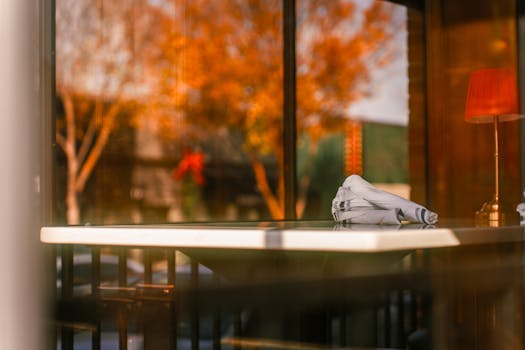 Warm ambiance at a restaurant table with a view of autumn leaves and soft lighting.
