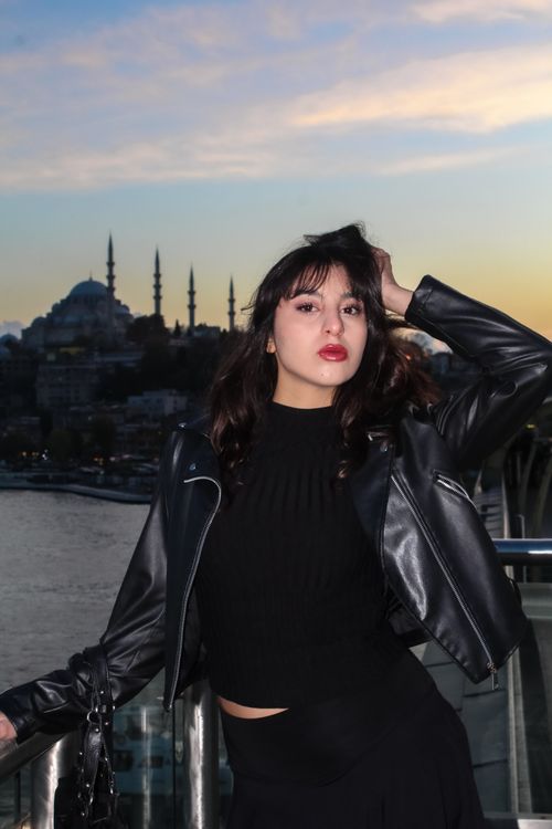 Free Stylish woman posing with Istanbul's skyline and mosque at sunset. Stock Photo