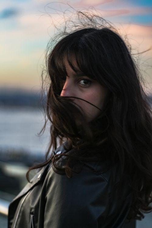 Free A moody portrait of a woman with flowing hair at sunset, capturing an urban atmosphere. Stock Photo