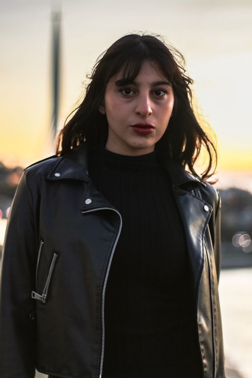 Free Portrait of a confident woman in a leather jacket with a sunset backdrop. Stock Photo