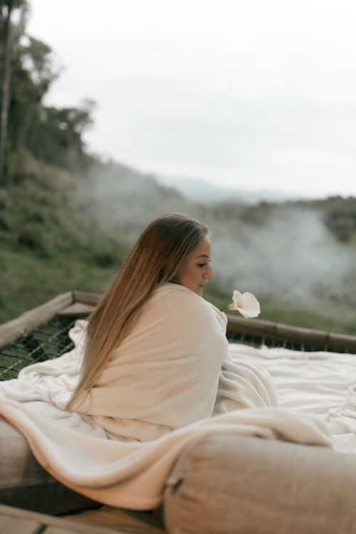 Free Serene outdoor scene of a woman wrapped in a blanket, enjoying nature's tranquility. Stock Photo