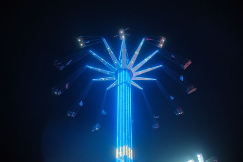 Free Photo of a blue-lit carnival swing ride against a dark night sky. Stock Photo