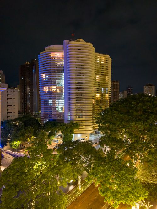 Free Illuminated skyscraper at night in Belo Horizonte, blending modern architecture with lush greenery. Stock Photo