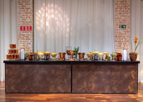 Stylish buffet table arrangement with copper accents and floral decor in a modern indoor setting.