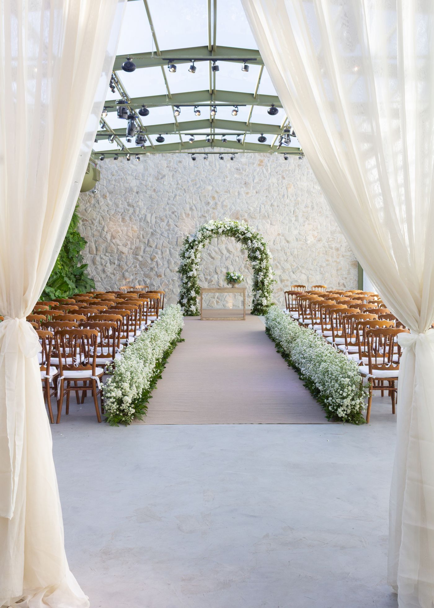 Elegant wedding ceremony with white floral arch and aisle flowers