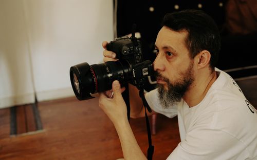 Free Focused photographer with camera, documenting an indoor setting, embodying creativity and precision. Stock Photo