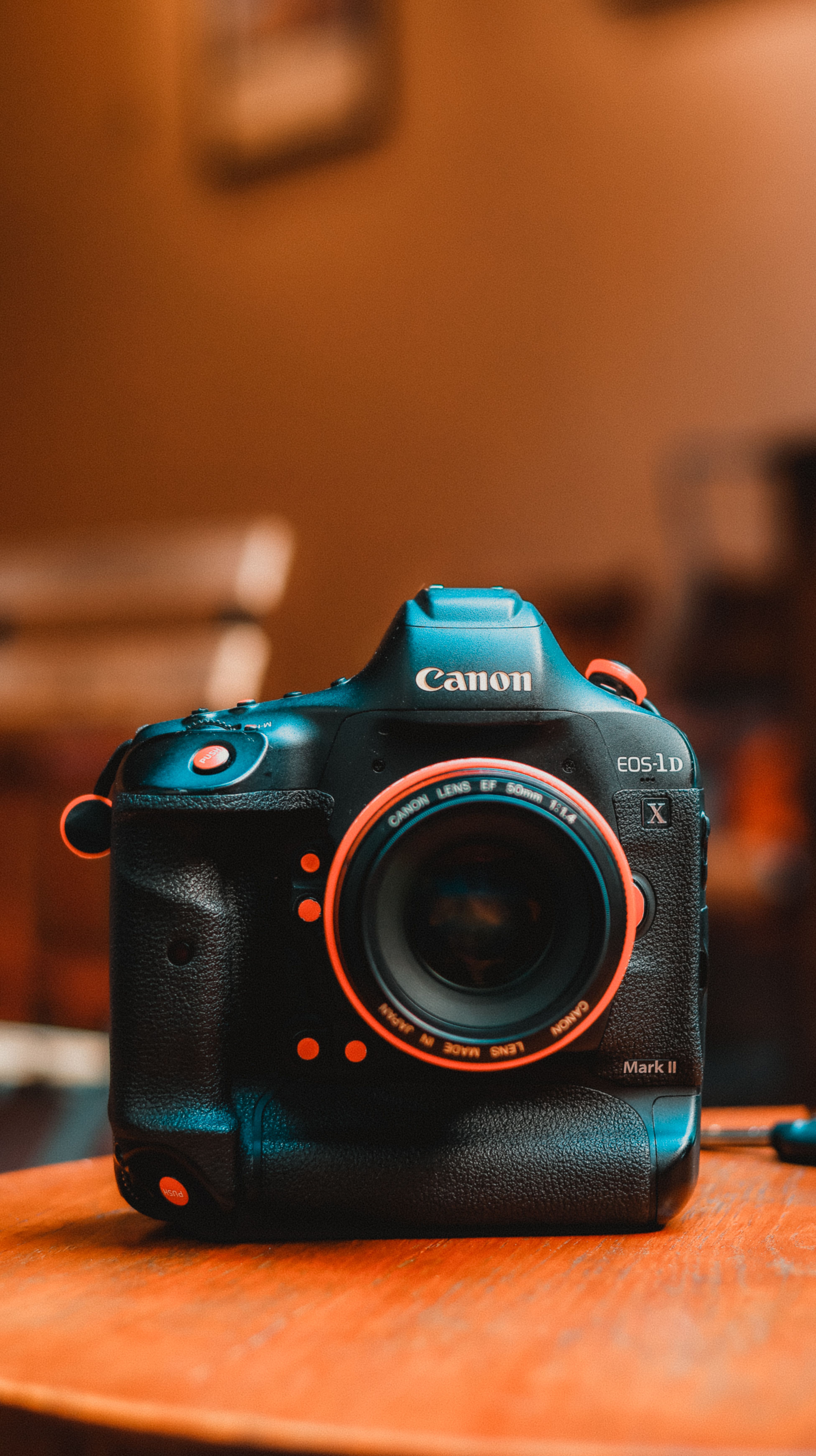 Close-up of a DSLR camera with lens on a wooden table indoors.