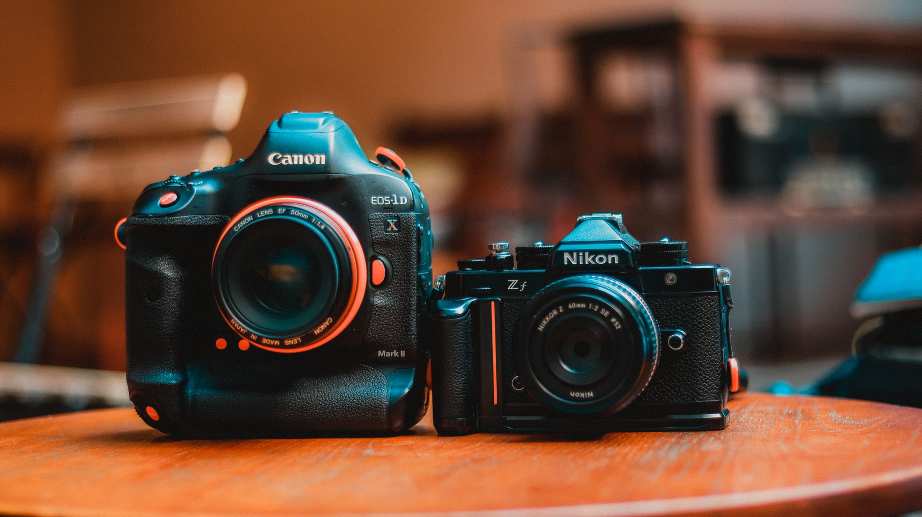 Close-up of Canon and Nikon cameras on a wooden surface indoors.