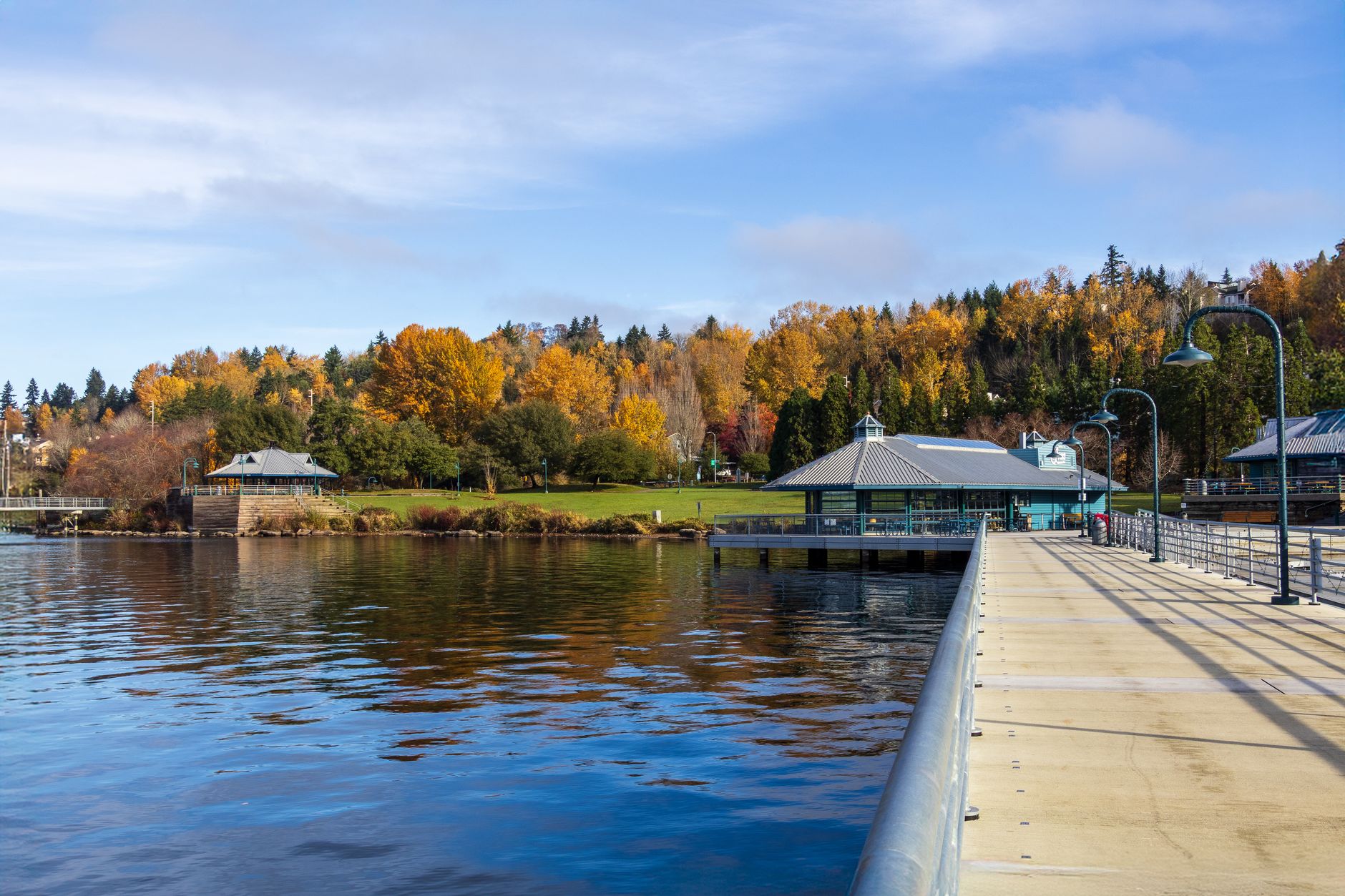 Beautiful lakeside view in fall with colorful foliage and a pier extending into the water.