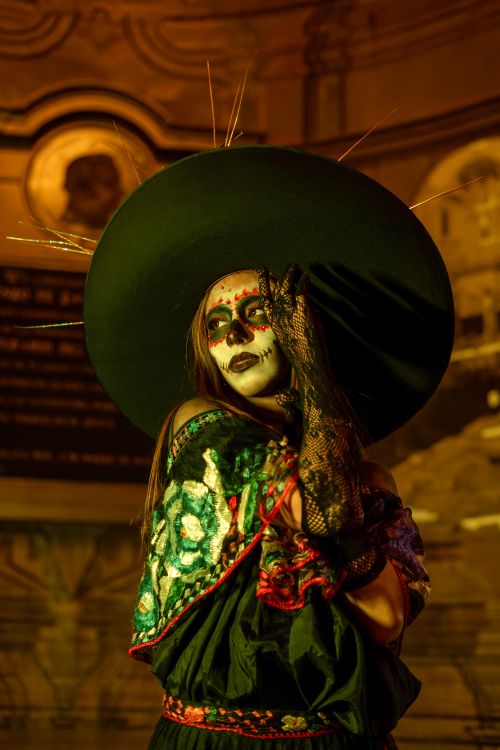 Free Woman in vibrant Dia de los Muertos costume with face paint and large hat. Night setting. Stock Photo