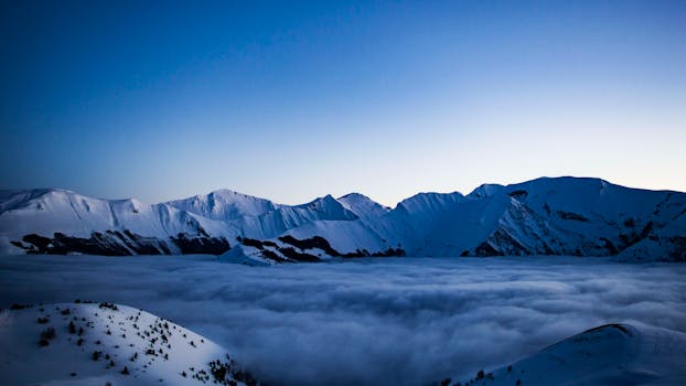 Explore the serene beauty of snow-capped mountains and clouds in Pintura, Italy.