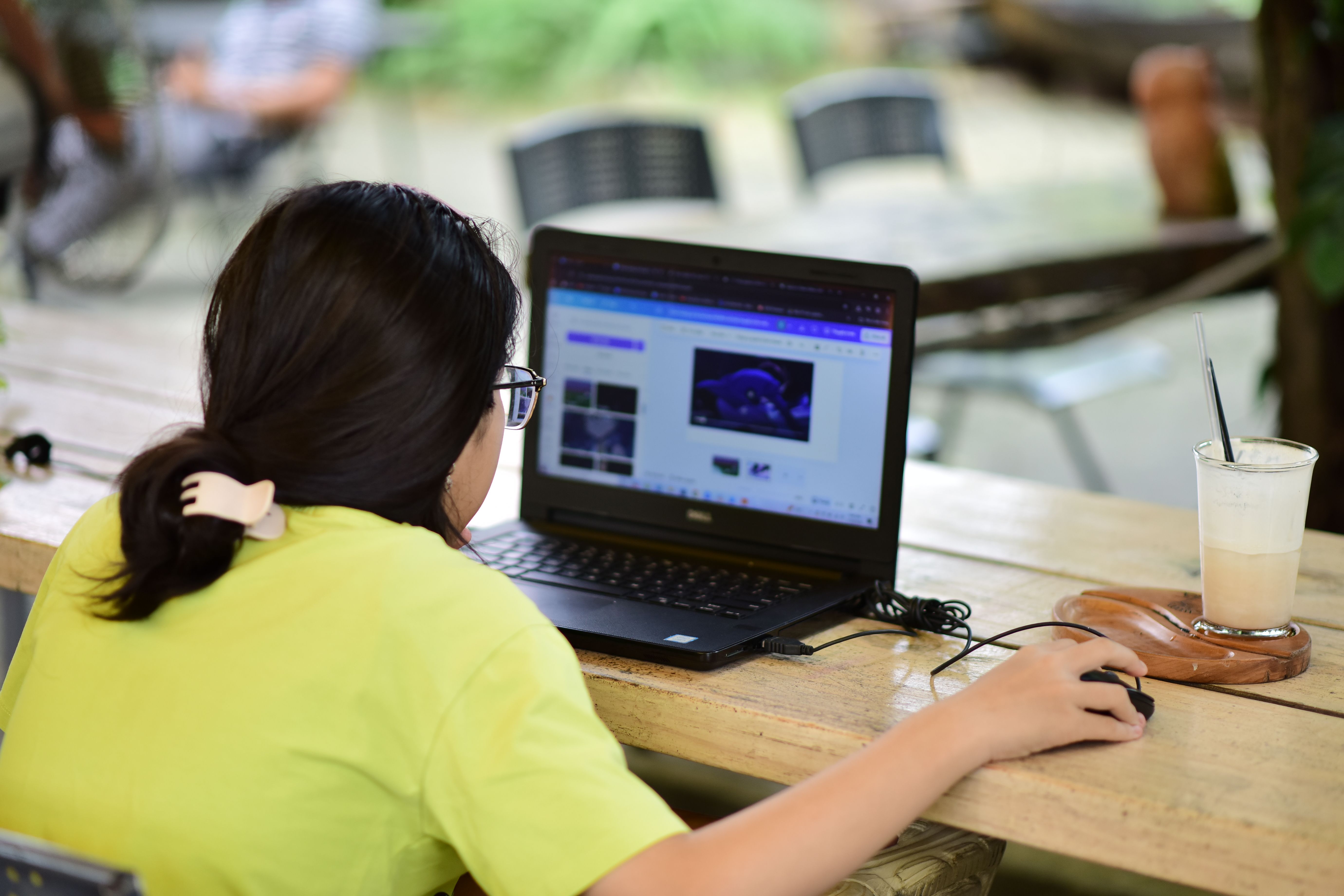 Woman Working on Laptop in Outdoor Cafe Setting