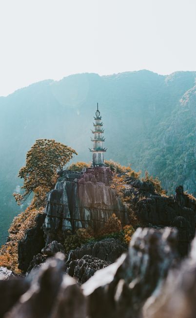 Breathtaking view of a pagoda atop rocky cliffs in Ninh Bình, Vietnam, surrounded by lush greenery.