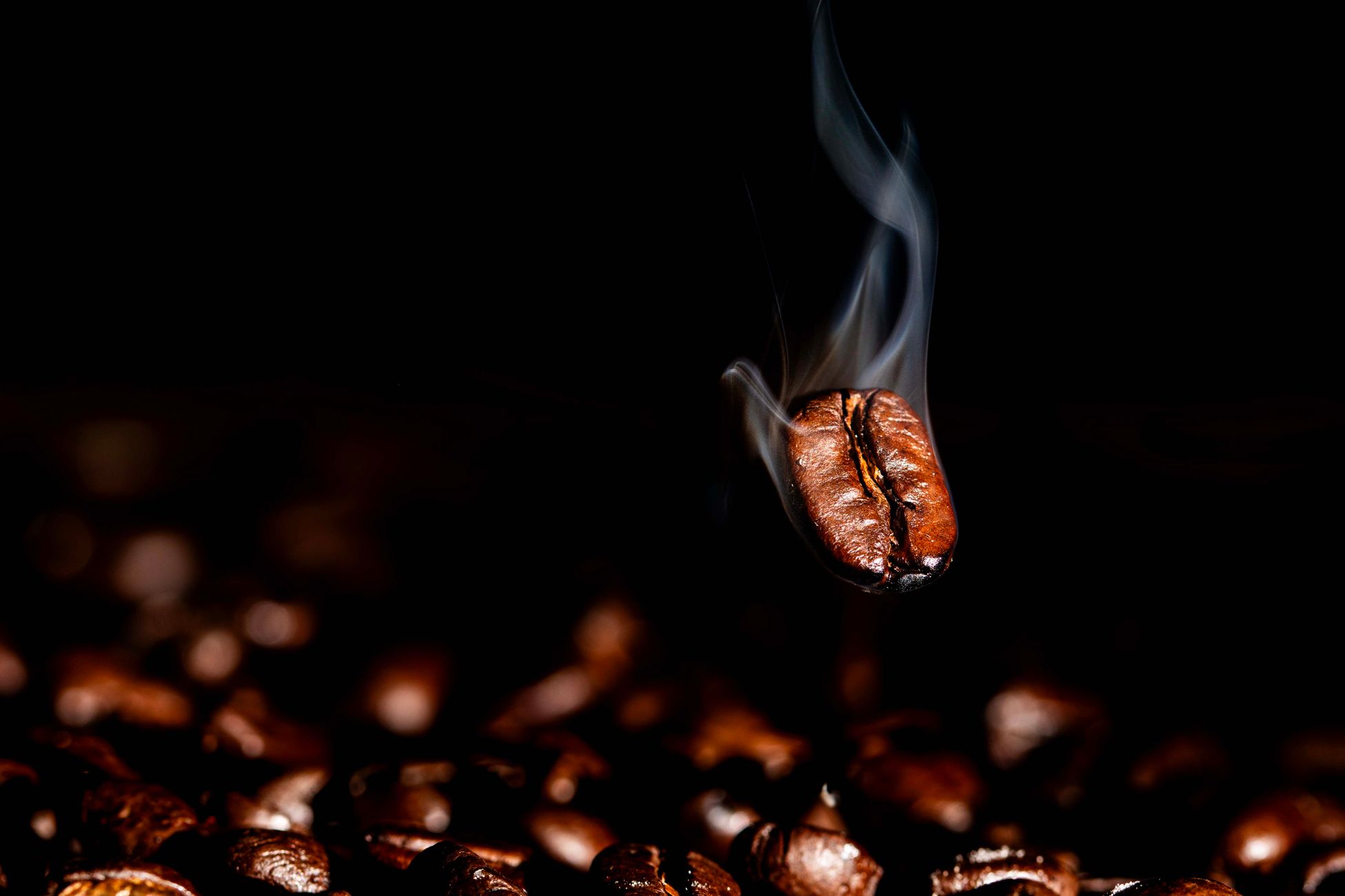 Close-up of a steaming coffee bean on dark background, showcasing roasting effects.