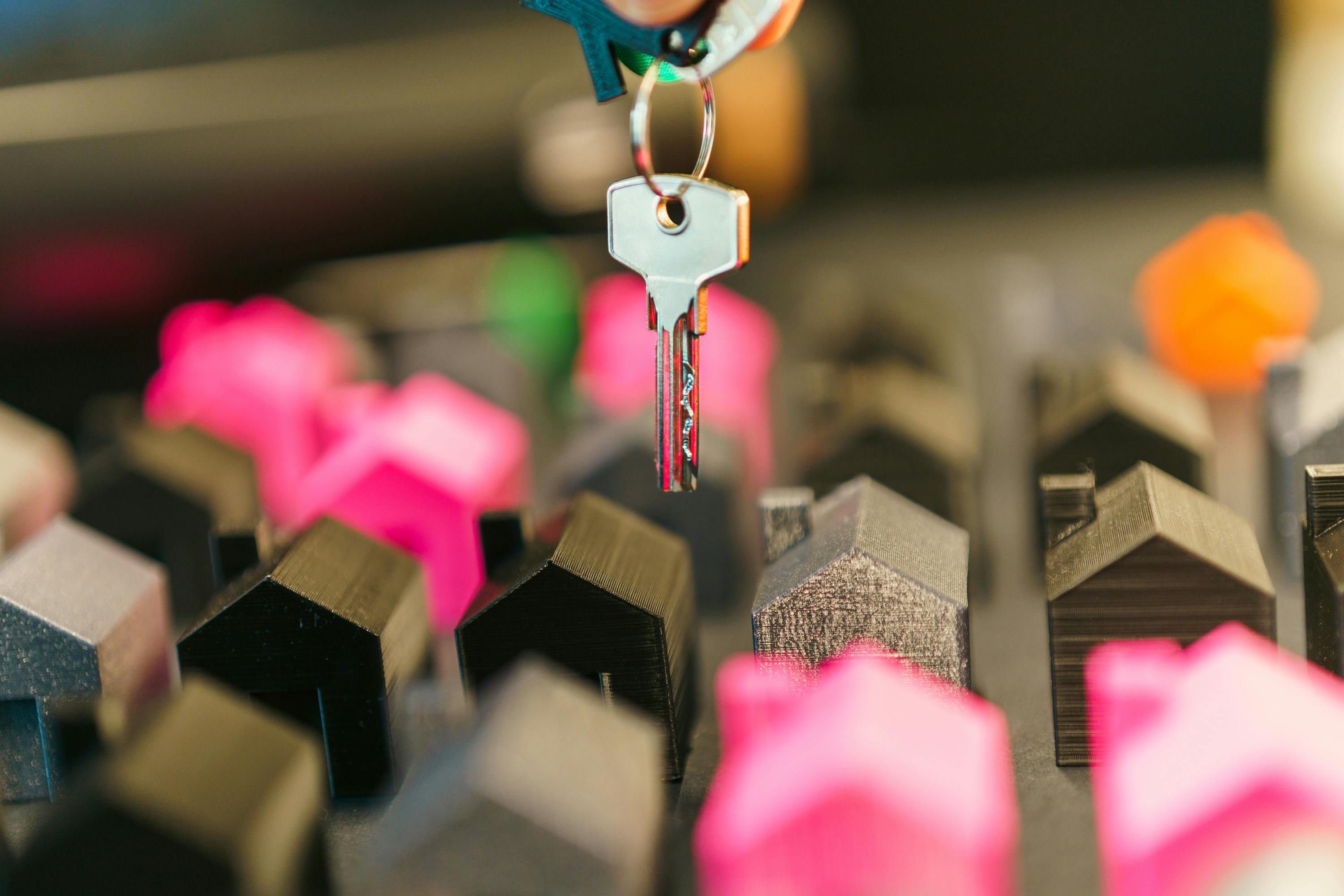 Image of a key dangling with multiple miniature houses in the background