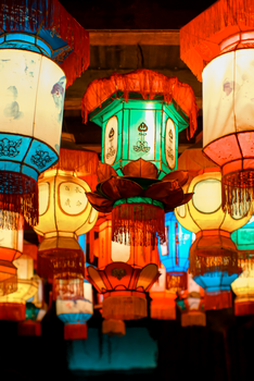 Colorful traditional Chinese lanterns illuminate an indoor celebration with vibrant hues.