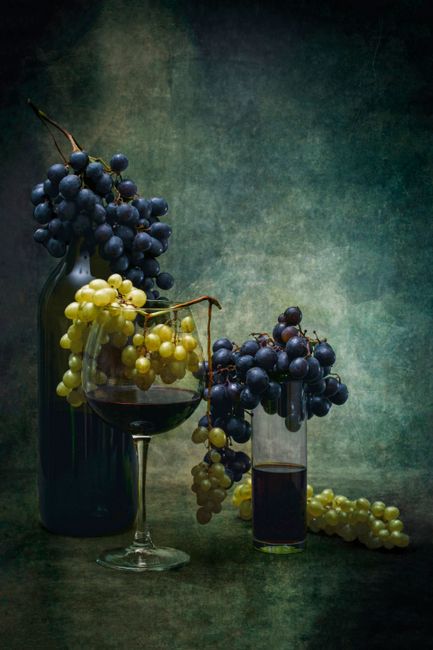 Elegant still life featuring grapes draped over wine glasses creating a classic scene.