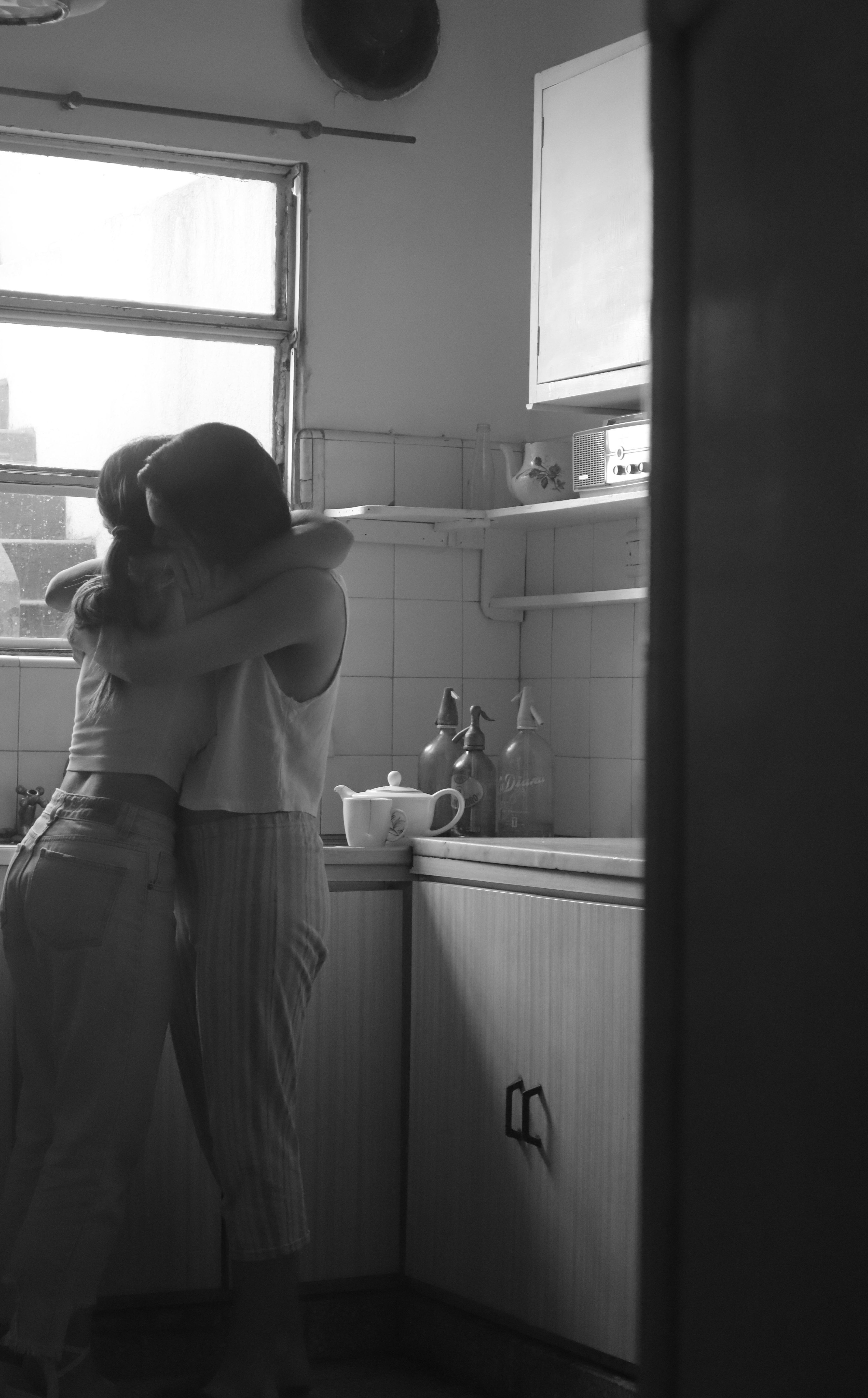 Intimate Hug in a Sunlit Kitchen · Free Stock Photo