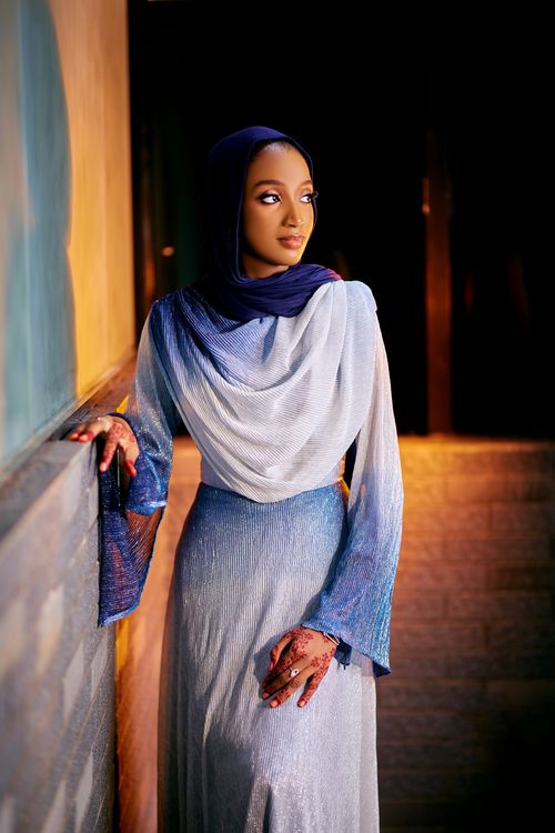 Free Woman in blue attire and hijab with henna, standing elegantly in soft lighting. Stock Photo