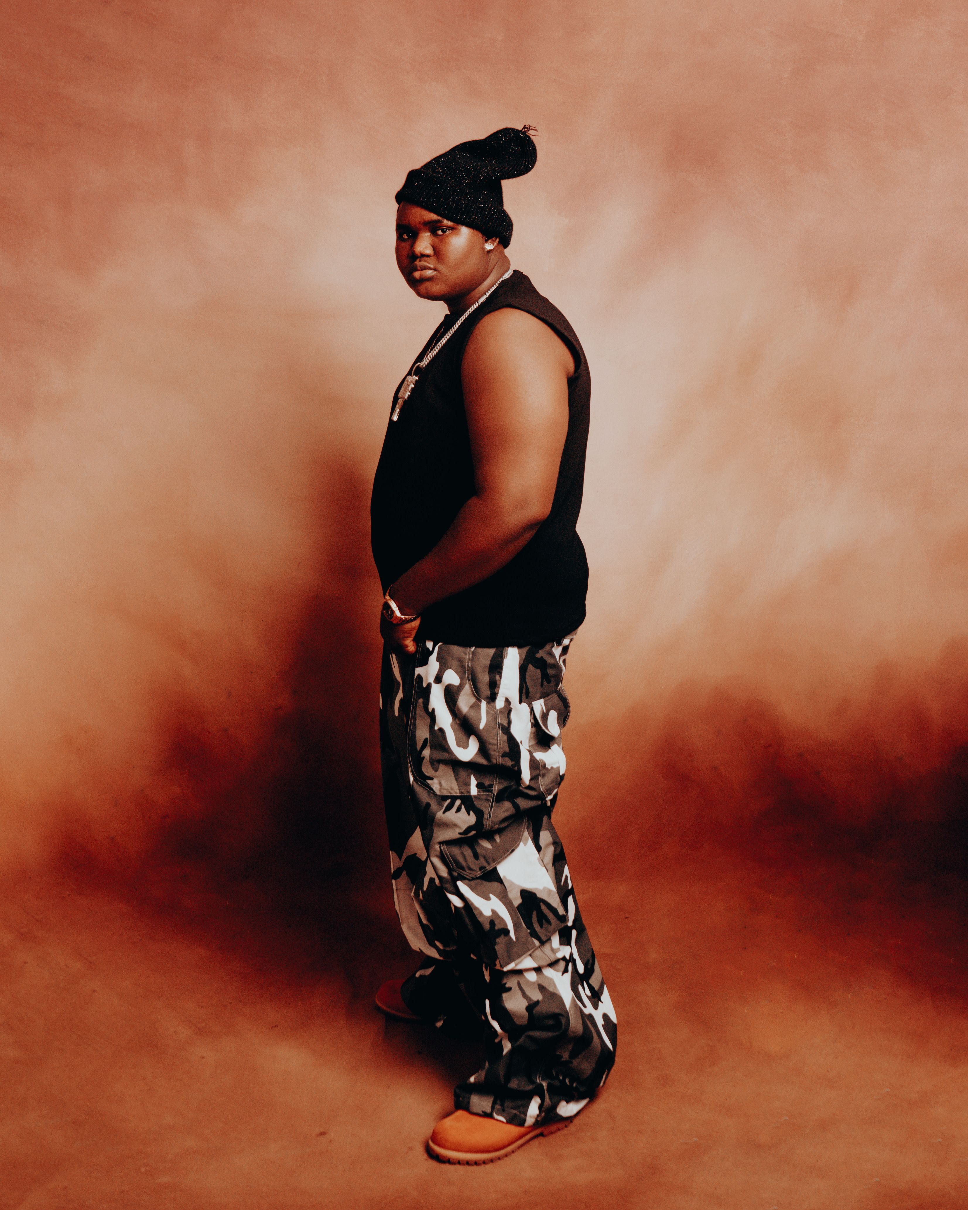 Stylish portrait of an individual in modern attire with a warm backdrop.