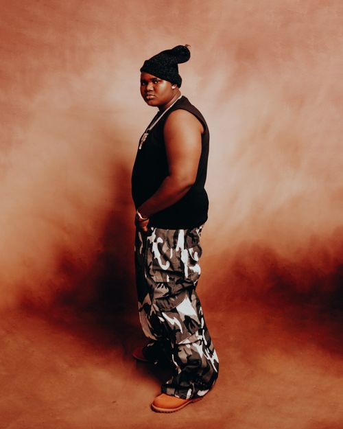 Free Stylish portrait of an individual in modern attire with a warm backdrop. Stock Photo