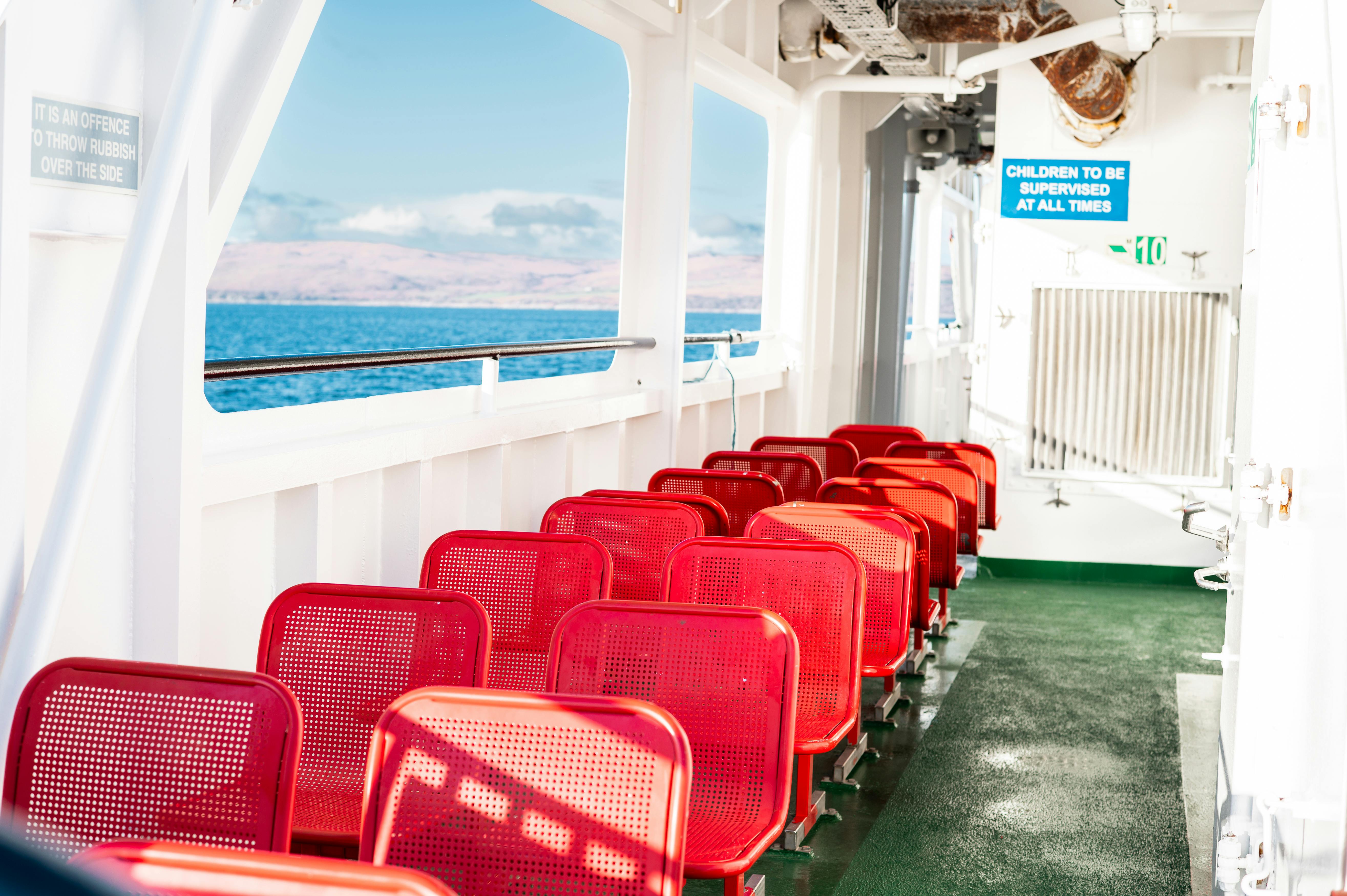 Empty red seats on a ferry with ocean views, captured in Scotland's scenic waters.