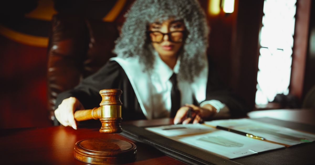 A judge in a courtroom holding a gavel and reviewing documents.
