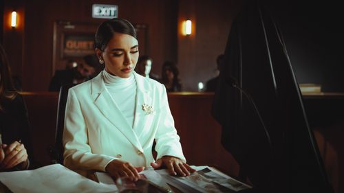 Free Elegant woman in a courtroom setting, reviewing documents with focus and confidence. Stock Photo