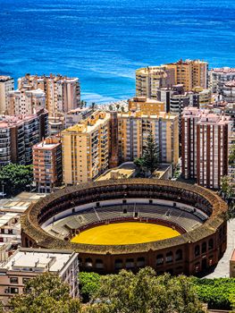 Aerial view of Málaga's Plaza de Toros and the Mediterranean Sea on a sunny day.
