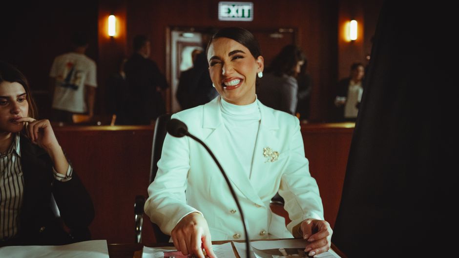 Mujer sonriente con traje blanco en un tribunal, transmitiendo profesionalismo y confianza.