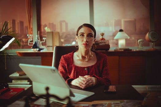 Woman in a modern office in Baghdad, Iraq, seated at a desk with a city view.
