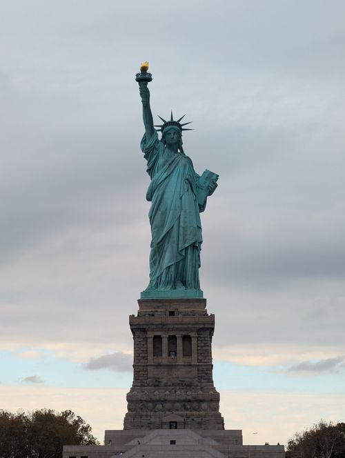 Free The Statue of Liberty stands majestically in New York with a cloudy sky backdrop, symbolizing freedom. Stock Photo
