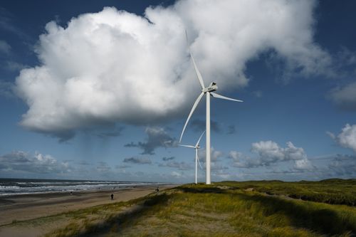 Free Wind turbines tower over a tranquil beach at Hvide Sande, Denmark, showcasing sustainable energy. Stock Photo