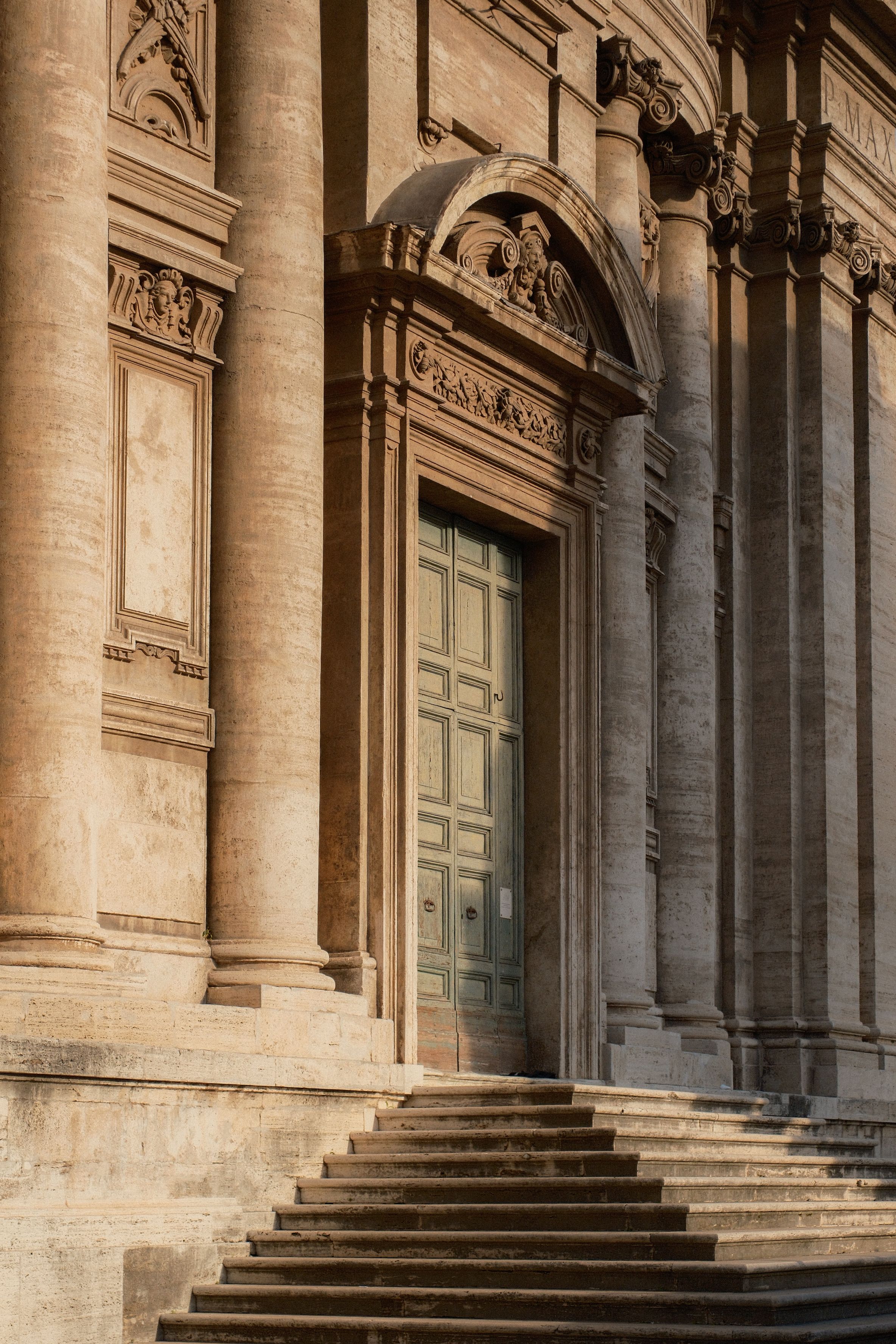 Sunlit basilica entrance with grand stone columns in traditional classical style.