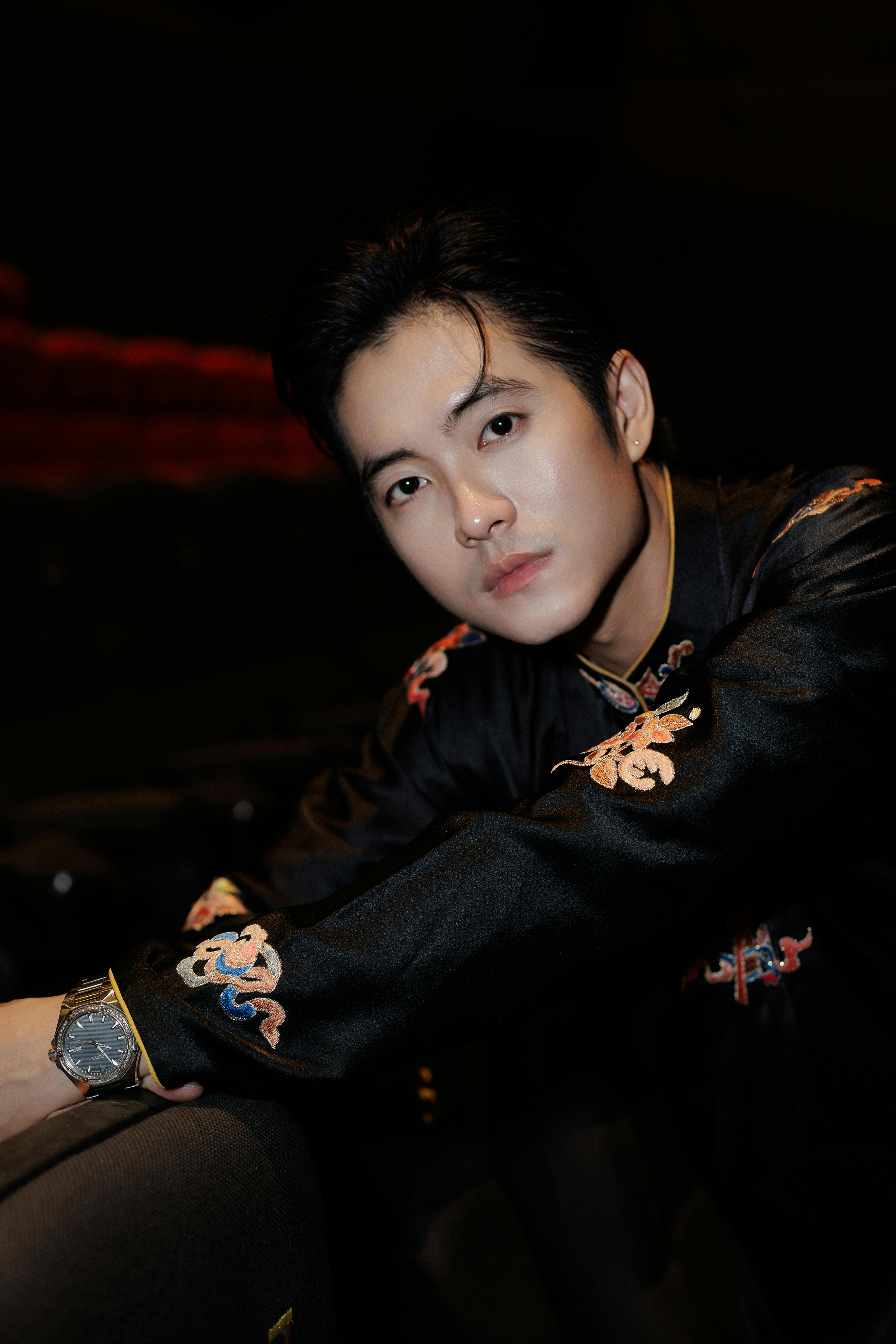 Sophisticated man wearing an embroidered jacket at an indoor event.