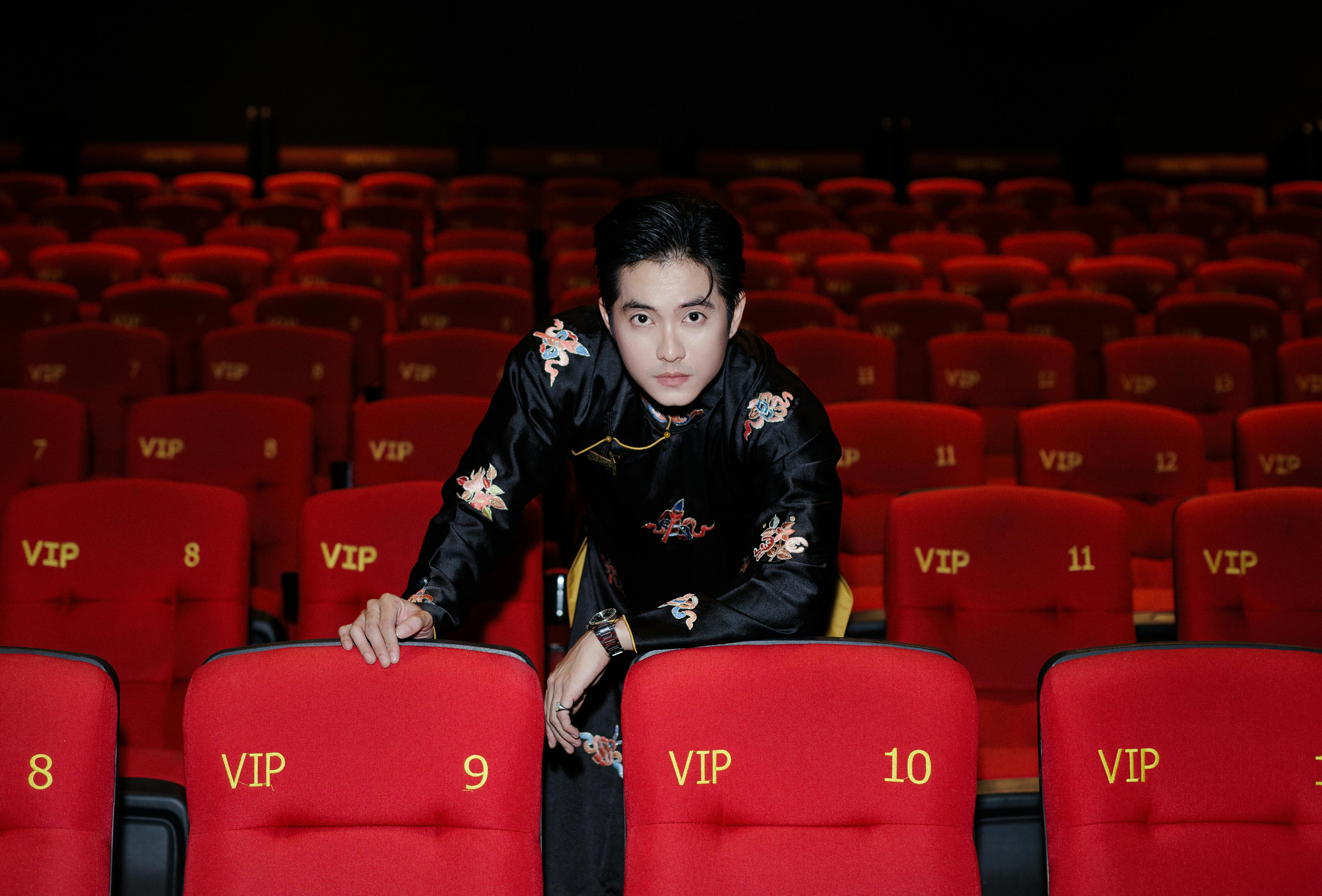 De franc Un home elegantment vestit posa amb confiança en una zona de butaques VIP de cinema, creant un ambient sofisticat i luxós. Foto d'estoc