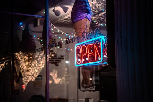 Illuminated neon open sign in a retro-themed ice cream shop window, creating a vintage ambiance.