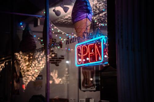 Free Illuminated neon open sign in a retro-themed ice cream shop window, creating a vintage ambiance. Stock Photo