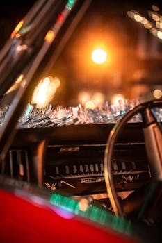 Close-up of a vintage car dashboard with glowing bokeh lights at night, creating a retro and moody atmosphere.