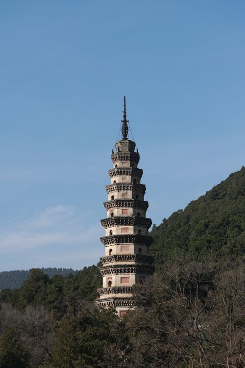 Free A striking ancient pagoda standing amidst lush green hills under a clear sky. Stock Photo