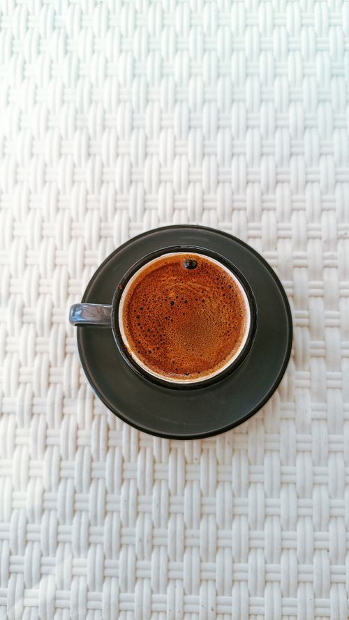 Free High-angle shot of steaming Turkish coffee in cup on textured tablecloth, perfect for coffee lovers. Stock Photo