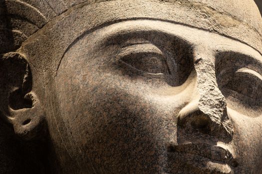 Detailed close-up of ancient Egyptian stone statue in warm lighting.