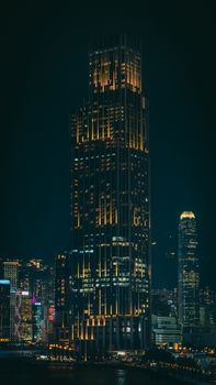 Tall skyscraper beautifully lit against night sky in bustling urban cityscape.