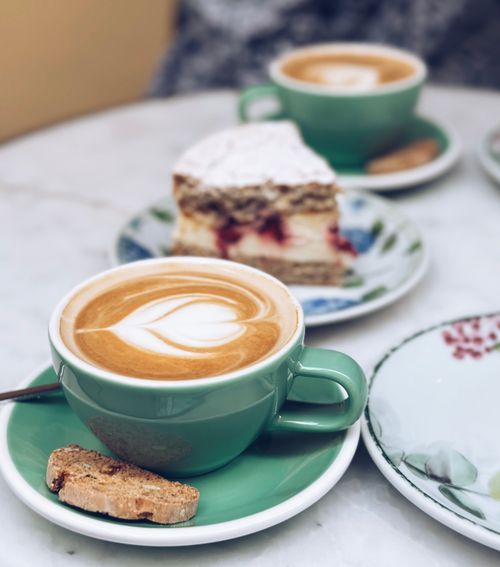 Free Enjoy a cappuccino with a biscotti beside a delicious dessert slice at a charming café in Istanbul. Stock Photo