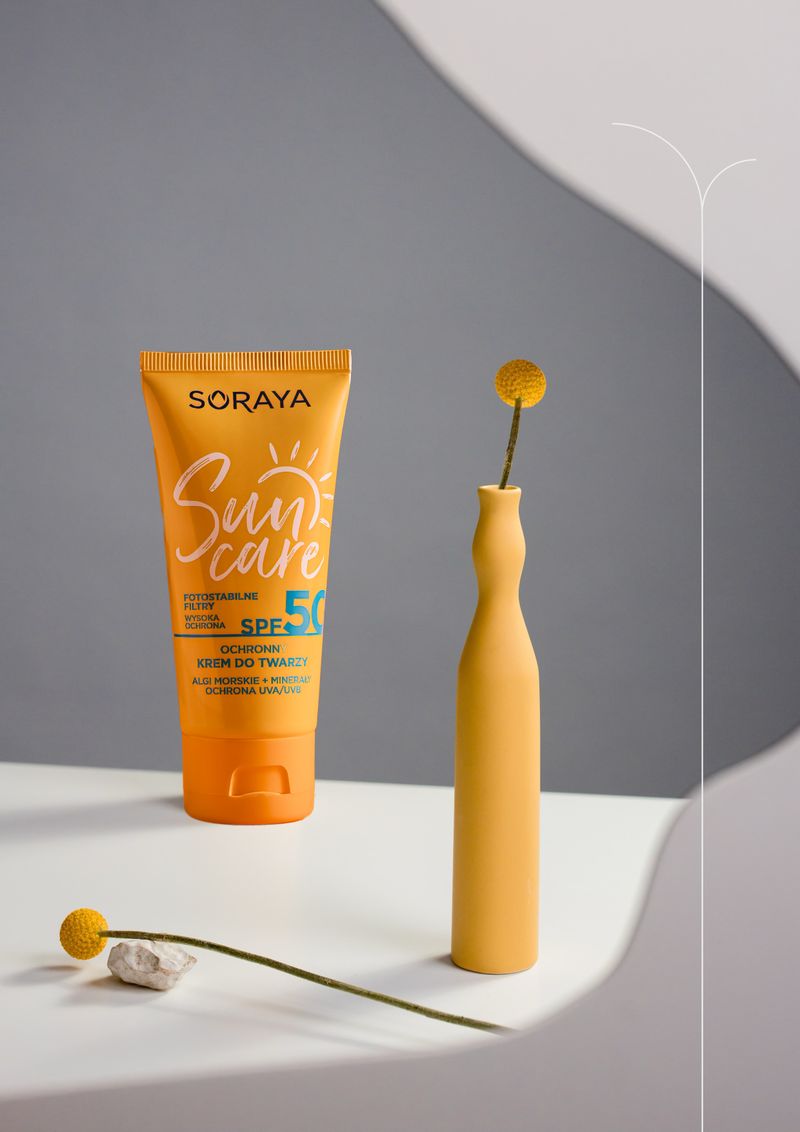 A sun care bottle beside a small vase on a clean neutral background