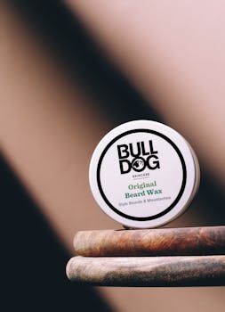 Close-up of Bulldog Original Beard Wax tin on a wooden surface, ideal for grooming beards.