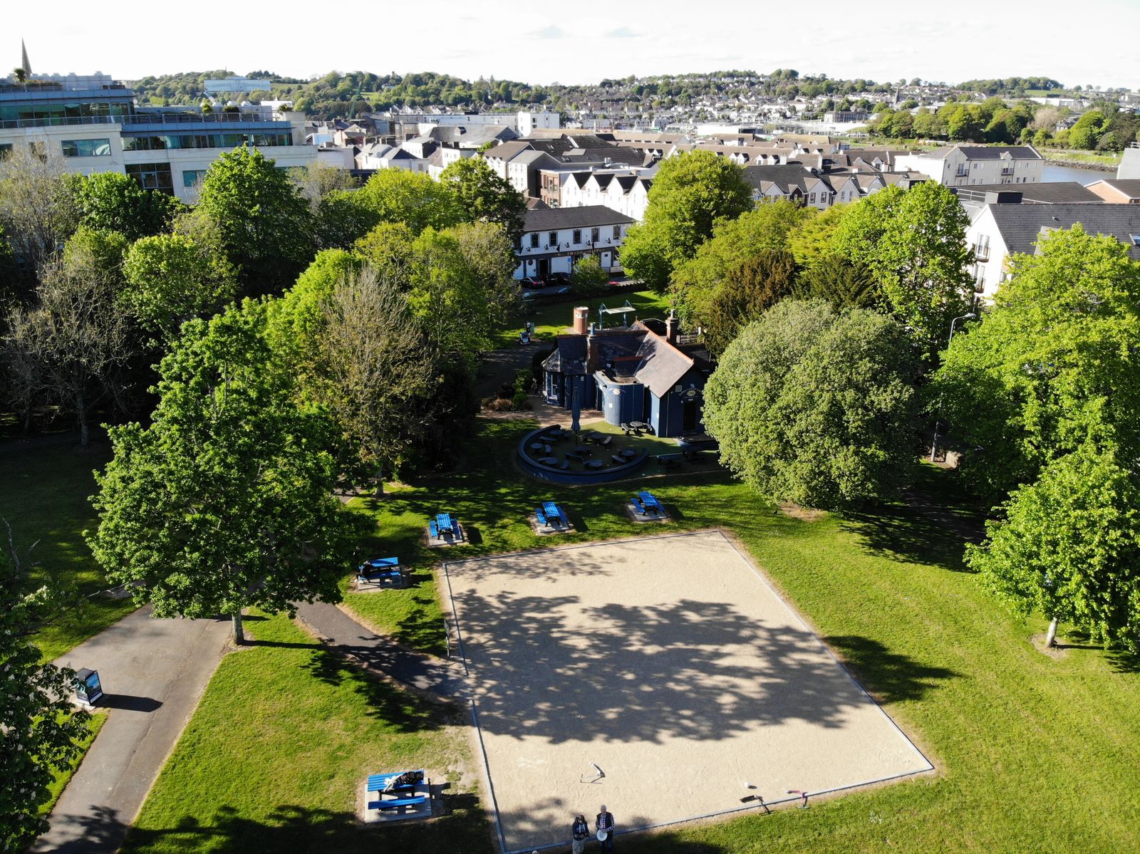 A aerial view of People's Park in Waterford, Ireland, featuring greenery and a bustling town backdrop