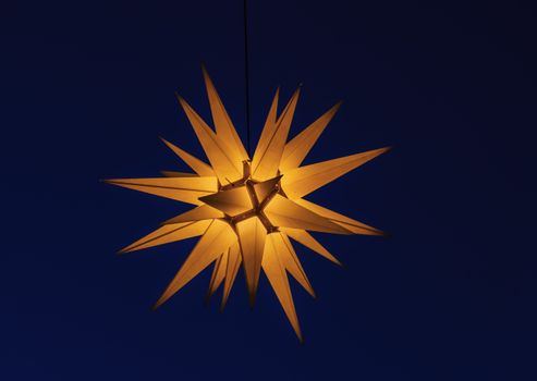 A glowing star-shaped Christmas light against a deep blue night sky, festive and decorative.